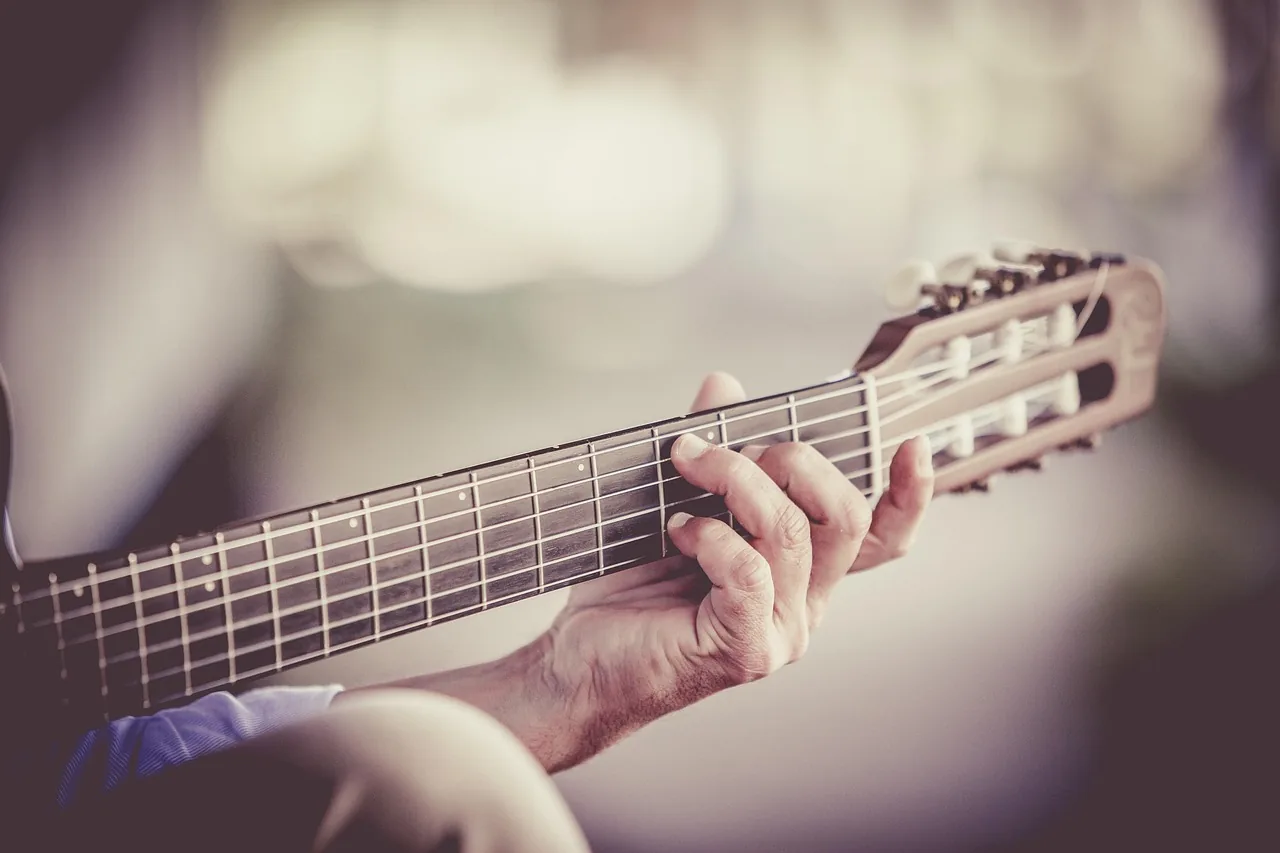 Doigts jouant des accords de guitare folk